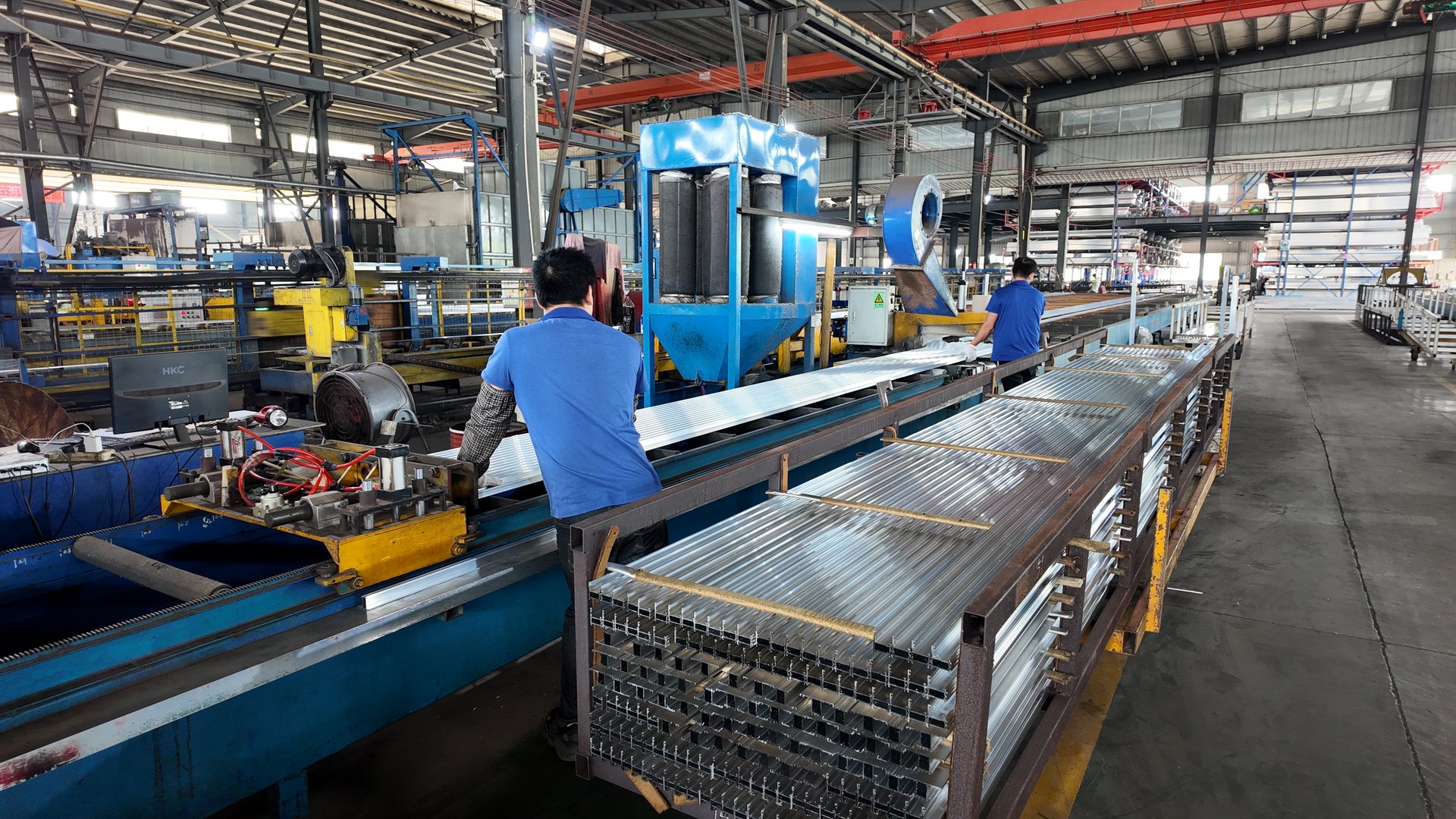 Operators handling aluminum profiles on the production line