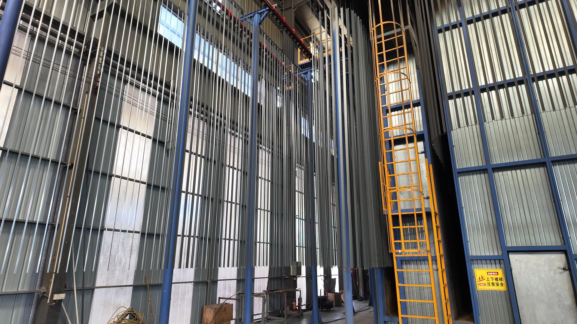 Vertical aluminum profiles suspended in the spray-coating line